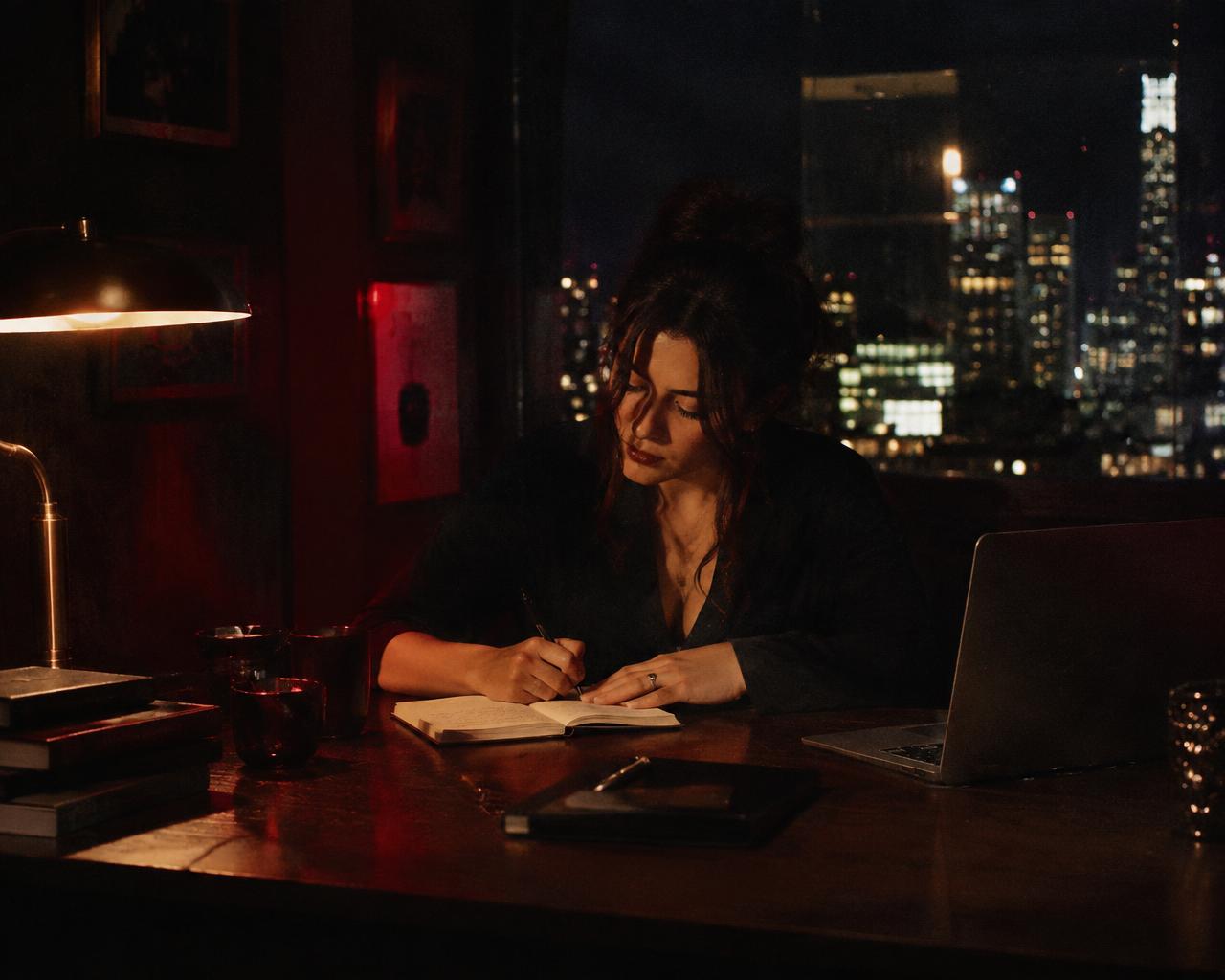 Woman writing in her journal at a desk late at night